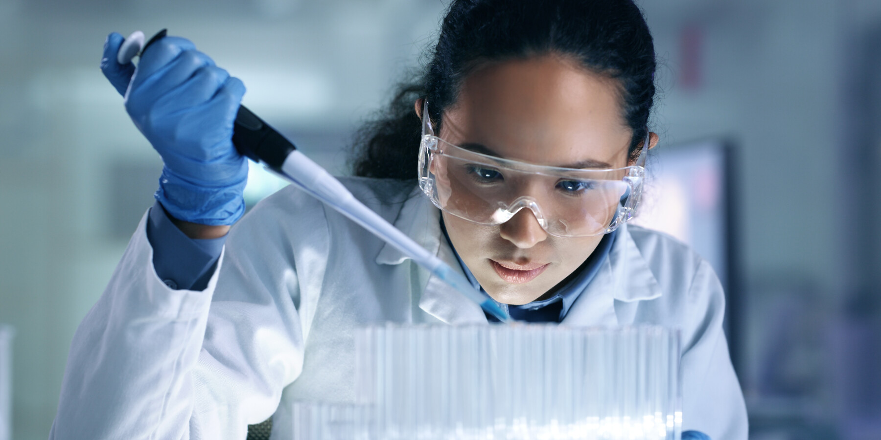 Scientist pipettes liquid into test tubes