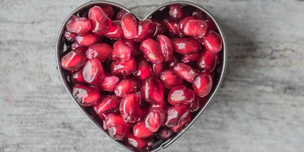 heart-shaped bowl filled with pomegranate seeds