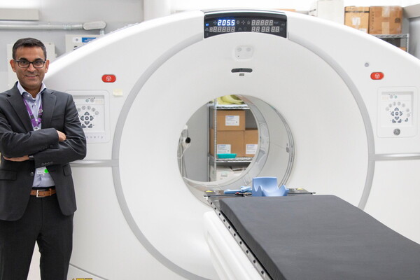 Neil Vasdev stands next to a CT machine.