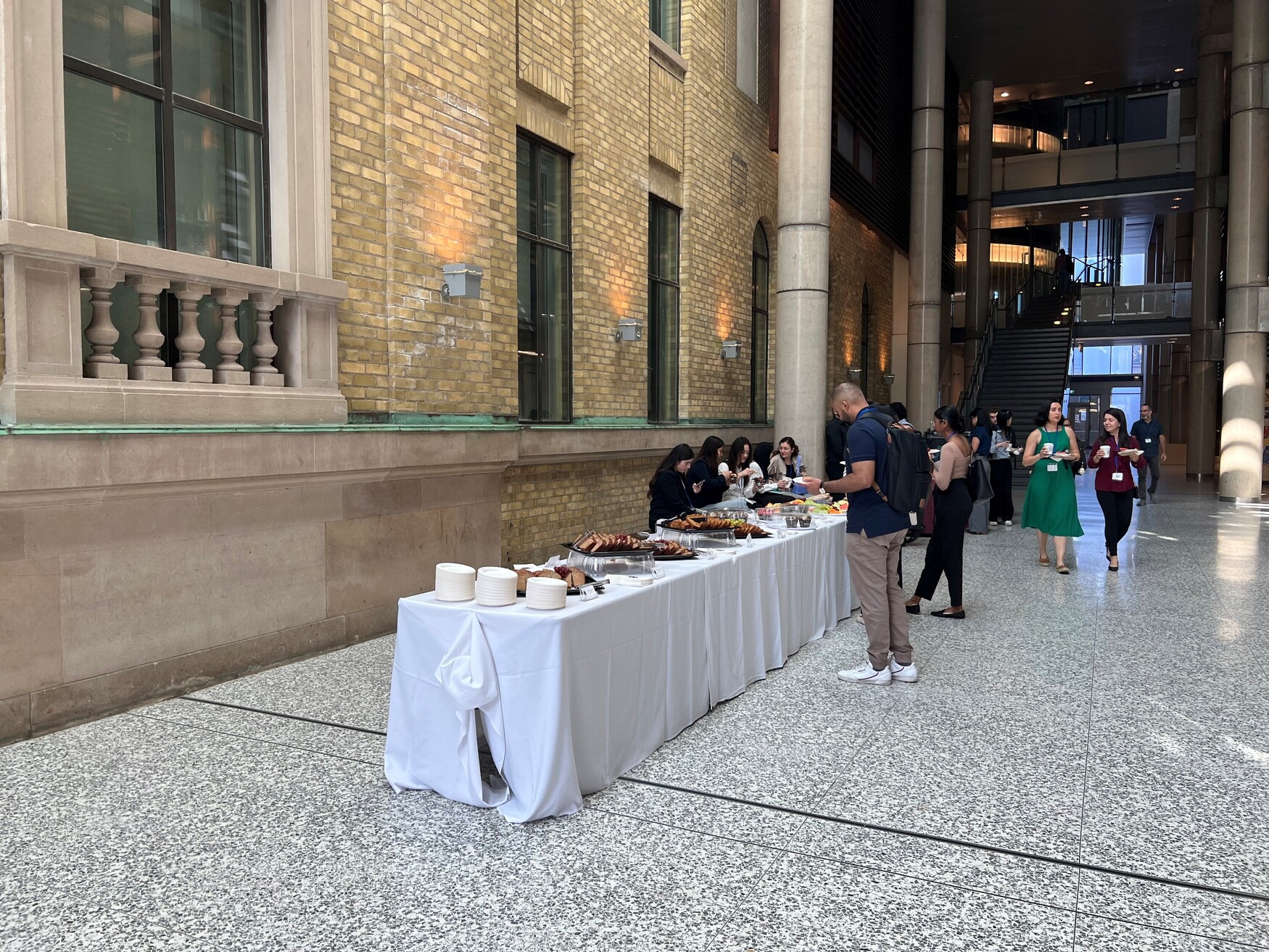 People in a foyer, gathering food from a buffet table